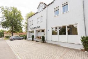 a white building with a car parked in front of it at Pension Lutter in Bodenwöhr