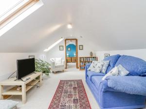 un salon avec un canapé bleu et une télévision dans l'établissement Shundraw Cottage, à Keswick