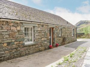 a stone house with a stone wall at Shundraw Cottage in Keswick
