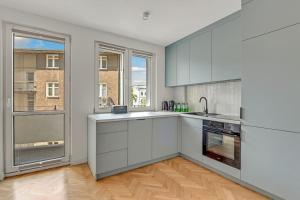 a kitchen with white cabinets and a large window at City Life - Gdynia by Grand Apartments in Gdynia
