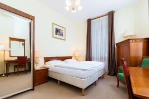 a bedroom with a bed and a mirror and a table at Spa Hotel Anglický Dvůr in Karlovy Vary