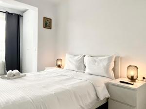 une chambre blanche avec un grand lit blanc et deux lampes dans l'établissement Astoria Apartment - Pet Friendly, à Braşov