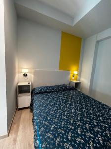 a bedroom with a bed with a blue bedspread at Hotel Sissi in Rimini