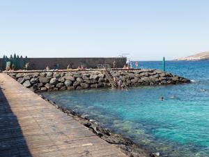 a beach with people swimming in the water at Live Puertito Neptune Beach in Puertito de Güímar