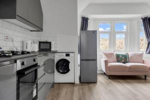 a kitchen with a washer and dryer and a couch at Modern Apartment in South West Wandsworth in London
