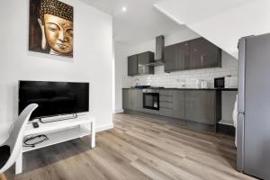 a living room with a television and a kitchen at Modern Apartment in South West Wandsworth in London