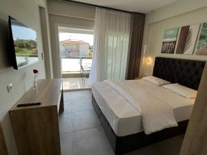 a bedroom with a bed and a television and a balcony at Astra Sarti Luxury Suites in Sarti