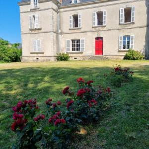 une maison avec une porte rouge et des fleurs dans la cour dans l'établissement Chambres d'hôtes Château de Saint Etienne du Bois, à Saint-Étienne-du-Bois
