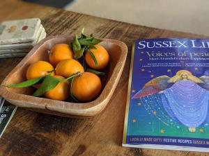 eine Schüssel Orangen auf einem Tisch neben einem Buch in der Unterkunft The Piggery in Cowfold