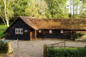 a small black house with a brown roof at The Piggery in Cowfold