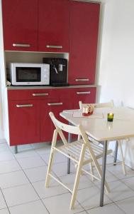 eine Küche mit roten Schränken, einem Tisch und einer Mikrowelle in der Unterkunft Castellane 15 minute Vélodrome Vieux-Port Plage in Marseille