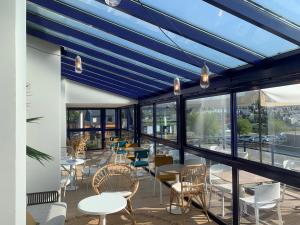 a restaurant with blue ceilings and tables and chairs at L'Escale Marine, The Originals Relais in Crozon