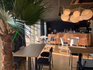 a restaurant with tables and chairs and a plant at L'Escale Marine, The Originals Relais in Crozon