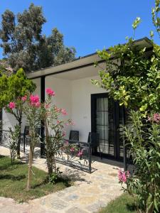 a house with a garden and some pink flowers at Otel Beyaz İnci in Palamutbuku