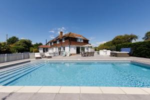 a large swimming pool in front of a house at Ultimate beach house with pool in West Wittering in West Wittering