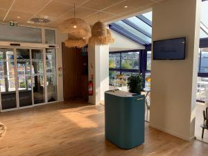 a lobby with a table and a tv in a building at L'Escale Marine, The Originals Relais in Crozon