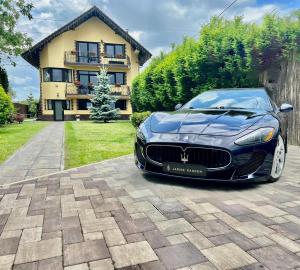 ein schwarzer Maserati vor einem Haus geparkt in der Unterkunft JANINE GARDEN in Braşov
