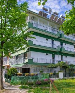 a green and white building with balconies and a tree at OLGA STUDIOS in Olympiaki Akti +21 photos