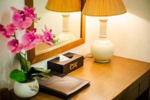 un escritorio con dos lámparas y un libro y flores. en One Hotel, en Hanói