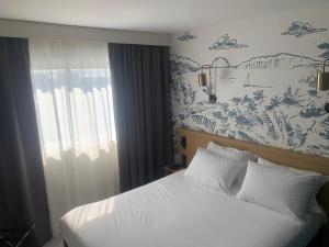a bedroom with a white bed and a wall mural at L'Escale Marine, The Originals Relais in Crozon