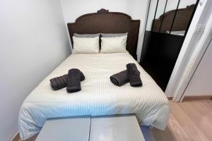 a bed with two pairs of black slippers on it at Very quiet apartment with balcony in Saint-Denis