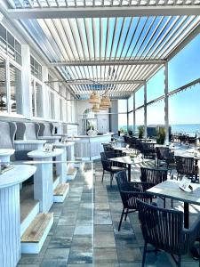 - un restaurant avec des tables et des chaises et une vue sur l'océan dans l'établissement meergut HOTELS, à Kühlungsborn