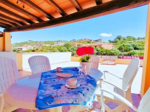 a glass table with white chairs and a blue table cloth at La Terrazza Di Porto Cervo in Porto Cervo