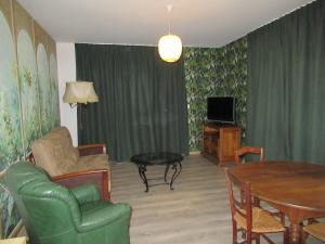 sala de estar con sofá, mesa y TV en Le gîte des fresques, en Saint-Savin