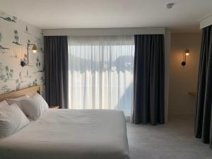 a bedroom with a bed and a large window at L'Escale Marine, The Originals Relais in Crozon