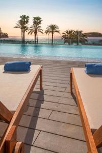 two beds on a deck next to a swimming pool at INNSiDE by Meliá Wave Calviá in Magaluf