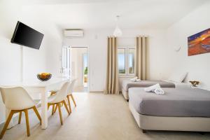 a hotel room with two beds and a table and chairs at Oniropetra Apartments Mykonos in Plintri