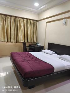 a bedroom with a large bed with a purple blanket at UK's Resort in Talegaon Dābhāde