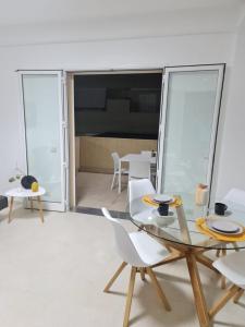 comedor con mesa de cristal y sillas blancas en Mediterraneo RELAX HOUSES en Marina di Ragusa