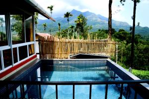 a swimming pool with a fence and mountains in the background at Mayflower Holiday Villa in Meppādi