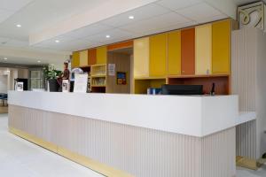 a lobby with a white counter and yellow cabinets at Hôtel Miléade Les Pléïades La Baule in La Baule +91 photos