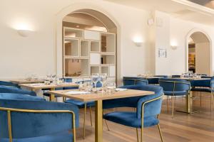 a dining room with tables and blue chairs at H&ocirc;tel Mil&eacute;ade Les Pl&eacute;&iuml;ades La Baule in La Baule