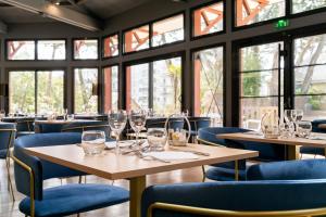 a restaurant with tables and chairs and windows at Hôtel Miléade Les Pléïades La Baule in La Baule