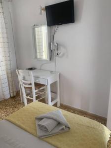 Cette chambre comprend un lit, une table et une télévision. dans l'établissement Korali Hotel, à Antiparos