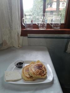 einen Teller Pfannkuchen auf einem Tisch mit einem Fenster in der Unterkunft комплекс Щастливците in Starozagorski Bani