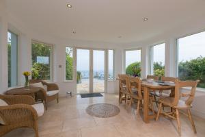 Un comedor con mesa y sillas y ventanas. en Moonbeams, en St Ives