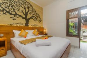 ein Schlafzimmer mit einem Bett mit einem Baumbild an der Wand in der Unterkunft Rahayu Guest House Ubud in Ubud
