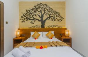 ein Schlafzimmer mit einem Bett mit einem Baum an der Wand in der Unterkunft Rahayu Guest House Ubud in Ubud