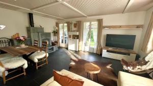 WirzweliにあるThe Swiss Paradise 2 Apartment with Garden, Whirlpool, and Mountain Panoramaのリビングルーム(テレビ、テーブル、椅子付)