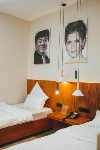 a bedroom with two beds and portraits of a man at Burundi Palace Boutique Hotel in Bujumbura