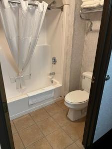 een badkamer met een toilet en een bad met een douchegordijn bij FairBridge Inn & Suites Williston in Williston