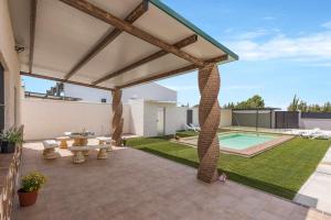 une terrasse couverte avec une table et une piscine dans l'établissement Casa Rural Rafael Lantejuela, à La Lantejuela
