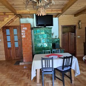 a dining room with a table and chairs and a tv at Domek Myśliwski z sauną 