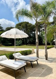 two beds and an umbrella on a patio at Villa Di Noi in Arnesano