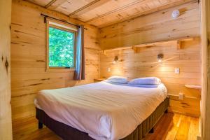 ein Schlafzimmer mit einem Bett in einem Blockhaus in der Unterkunft Village Huttopia Senonches - Perche in Senonches
