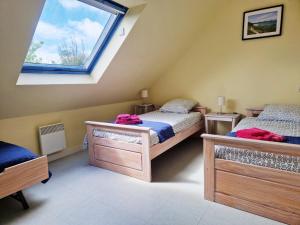 a attic bedroom with two beds and a window at Les Maisons de Kerdavid'île in Locmaria